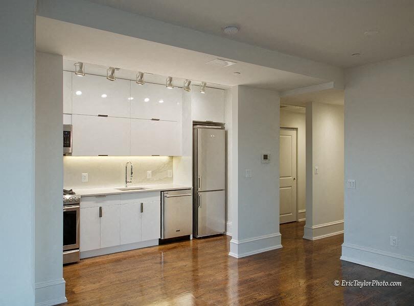 an empty kitchen with white cabinets and a stainless steel refrigerator