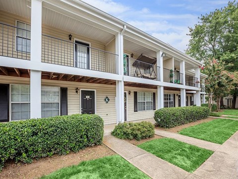 a white apartment building with a porch and a sidewalk