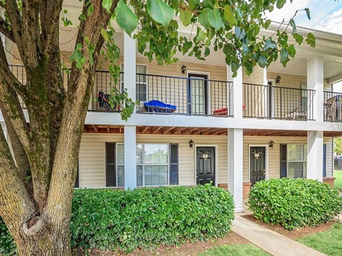a house with a balcony and a tree in front of it
