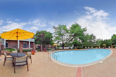 our resort style swimming pool is surrounded by patio furniture and umbrellas