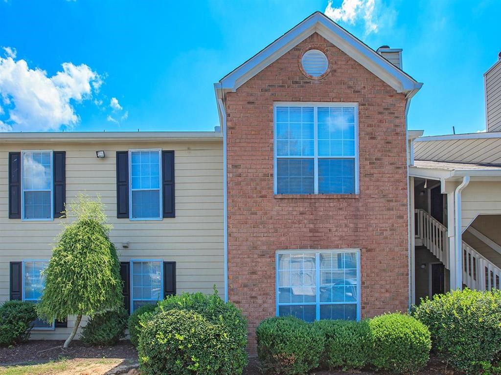the front of an apartment building with shrubs and trees