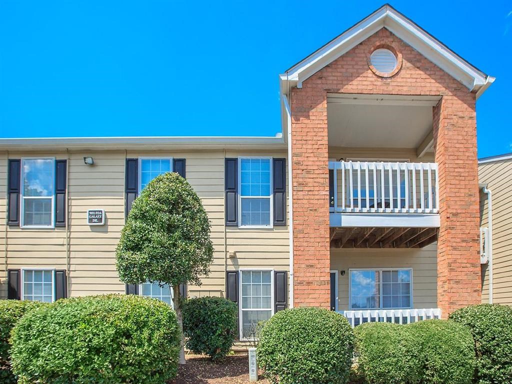 the front of an apartment building with bushes and a tree