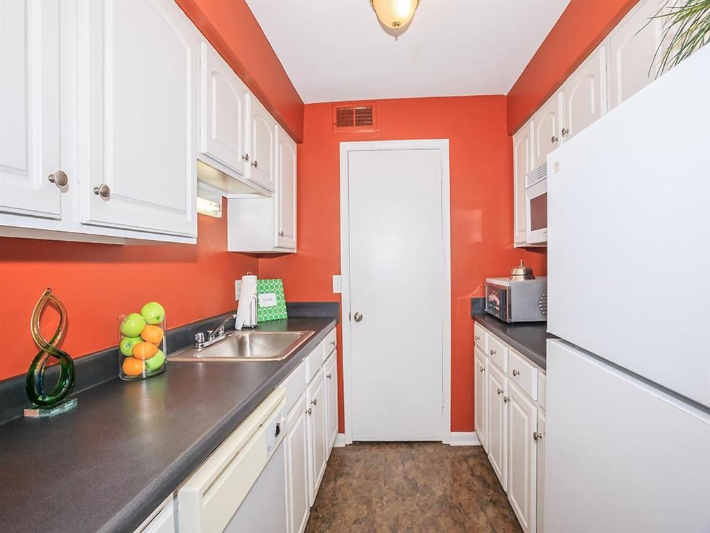 a kitchen with white cabinets and a sink and a refrigerator