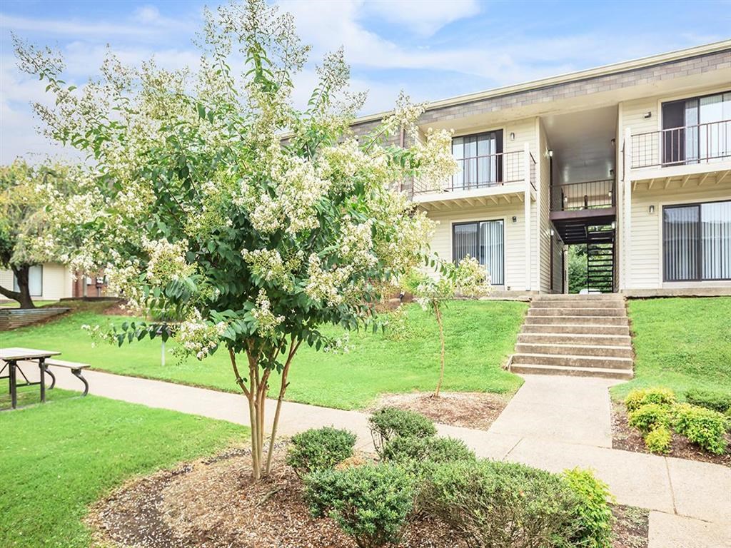 a building with a sidewalk and a tree in front of it
