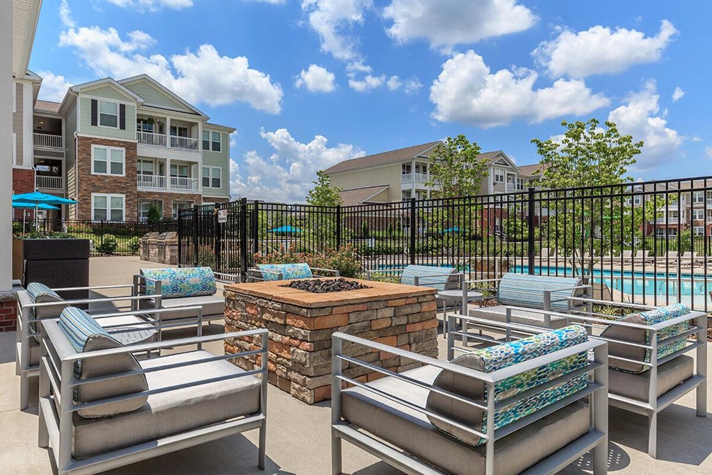an outdoor patio with lounge chairs and a pool with an apartment building in the background