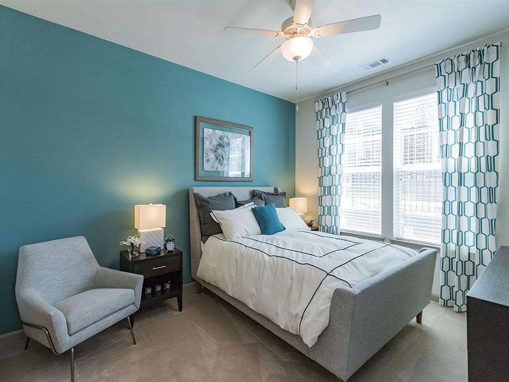 a bedroom with a bed and a chair and a ceiling fan