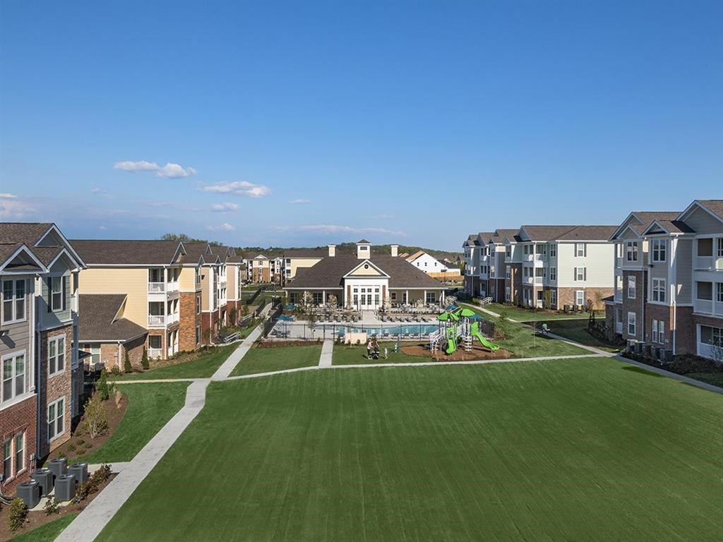 an aerial view of an apartment complex with a pool and lawn