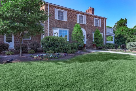a red brick house with a lawn in front of it