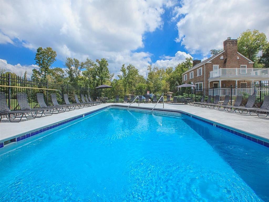 a large pool with chairs around it in front of a house
