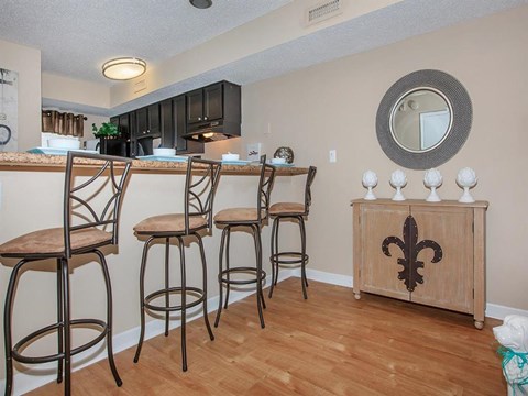 a living room with a bar with three chairs