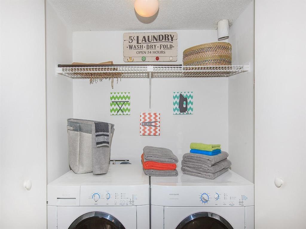 a white laundry room with washing machines and towels