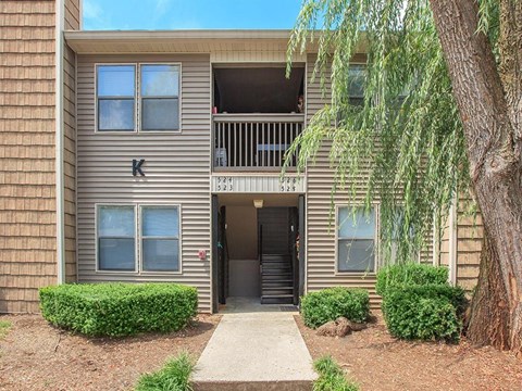 an apartment building with a balcony and a tree