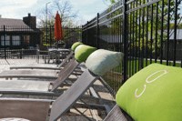 a picnic table with green chairs and a black fence
