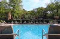 a swimming pool with chairs and trees in the background