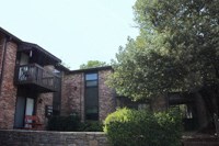 a brick house with a balcony and a tree
