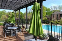 a patio with tables and umbrellas next to a swimming pool