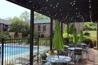 a patio with tables and umbrellas next to a swimming pool