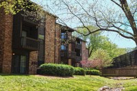 an apartment building with a green lawn and trees