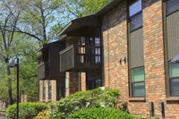 a brick apartment building with a balcony and trees