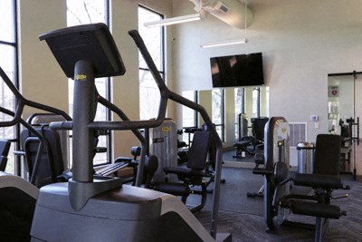 a gym with various machines and chairs and a tv
