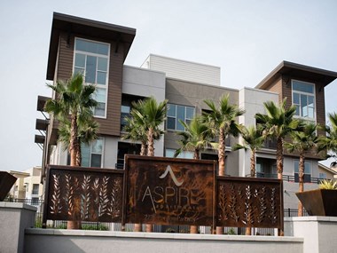Luxury Apartments for Rent in Tracy- Aspire-Tracy, CA-Property Sign, Palm Trees, White and Brown Building, and Private Balconies