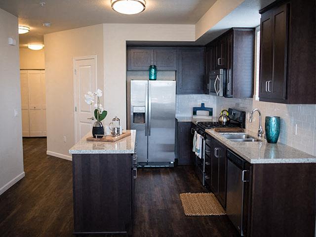 Tracy Apartments -Aspire-Tracy, CA-Dark Wood Cabinets, Grey Countertops, Stainless Steel Appliances, and a Kitchen Island