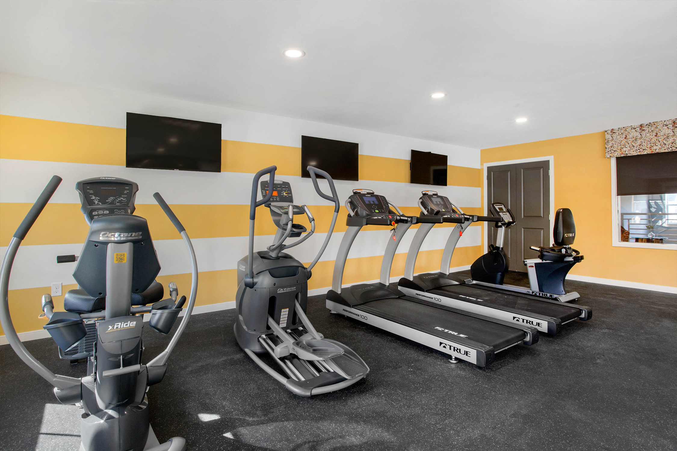 a gym with cardio machines and flat screen televisions
