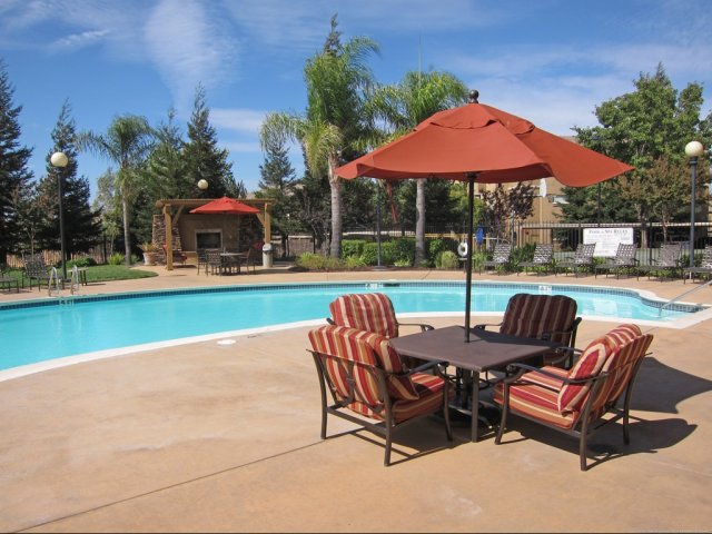 Roseville Apartments for Rent - Pinnacle at Galleria - Outdoor Pool With Glistening Water, Handrails on Each End, and Table Seating With Umbrella Coverings