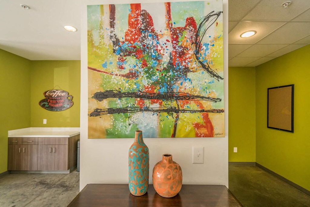 a painting on the wall in a room with a table and vases