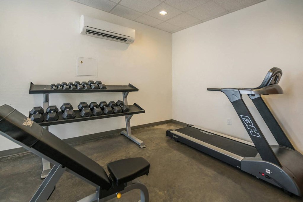 a gym with treadmills and weights in the corner of a room