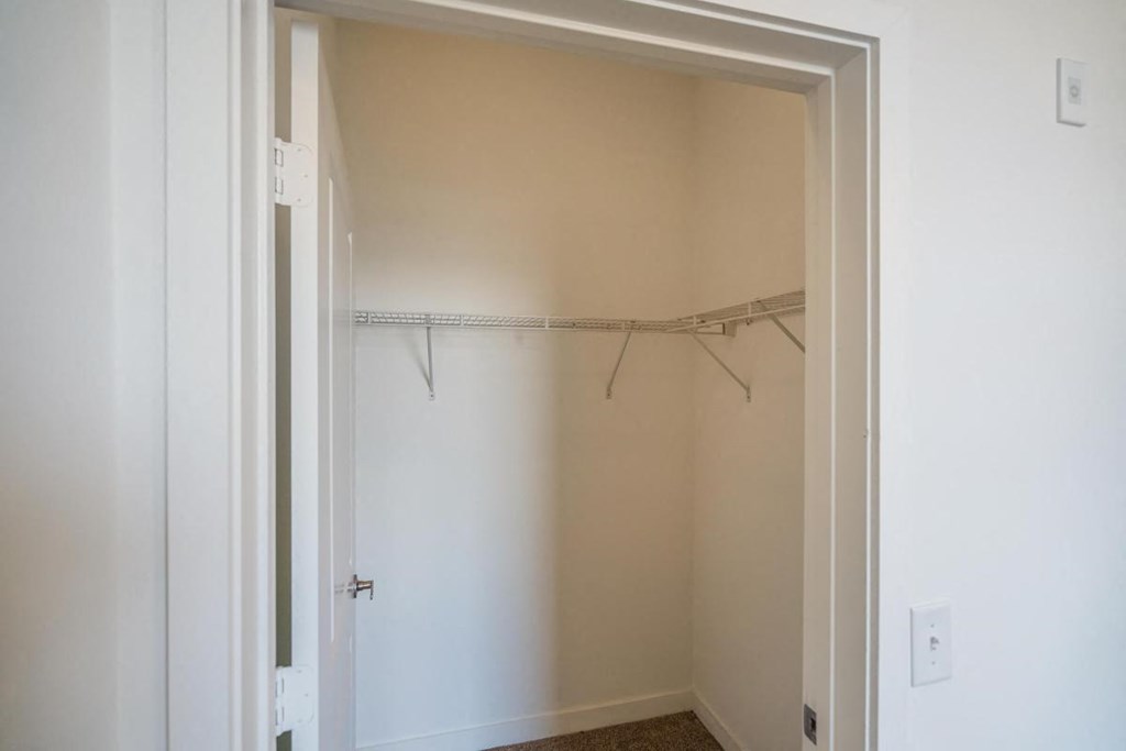 a walk in closet with a mirrored closet door and a clothes rack