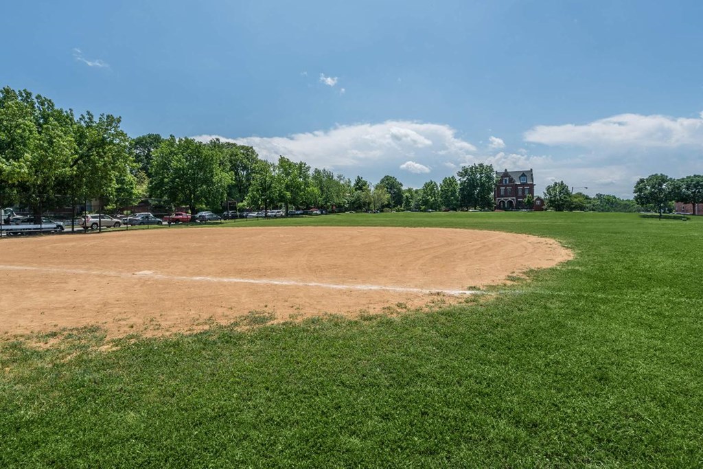 a baseball field with green grass and a blue sky