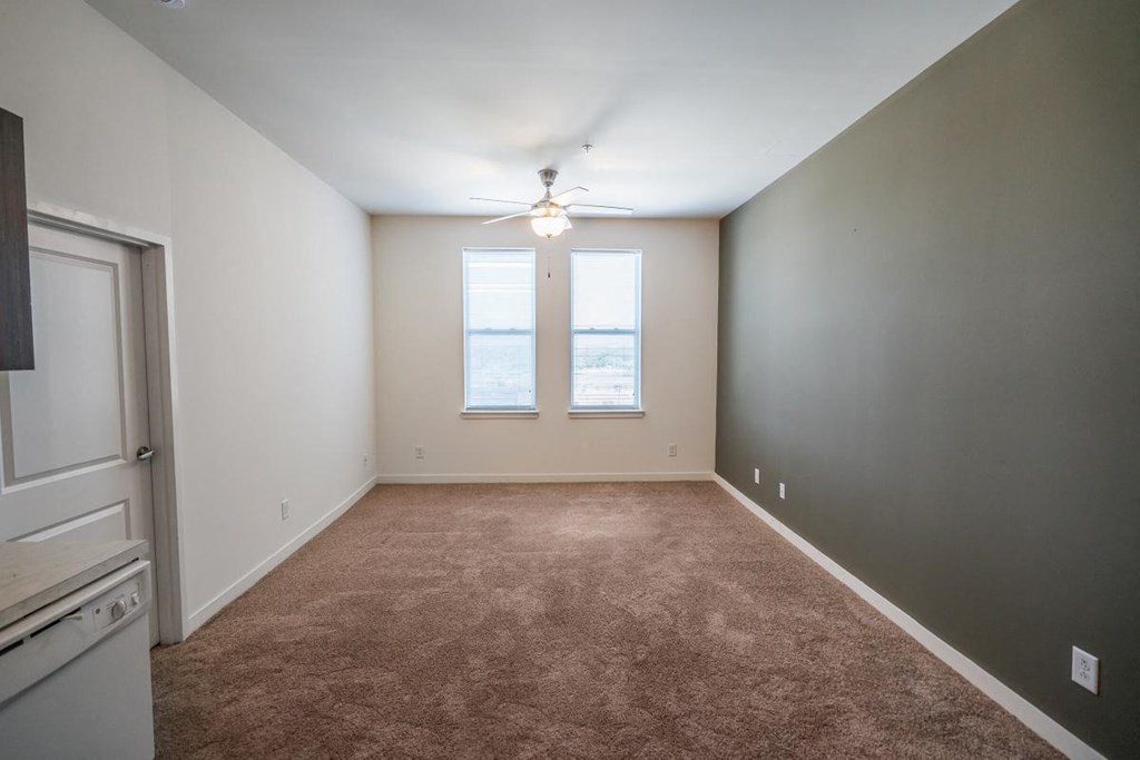 an empty living room with a ceiling fan and a window
