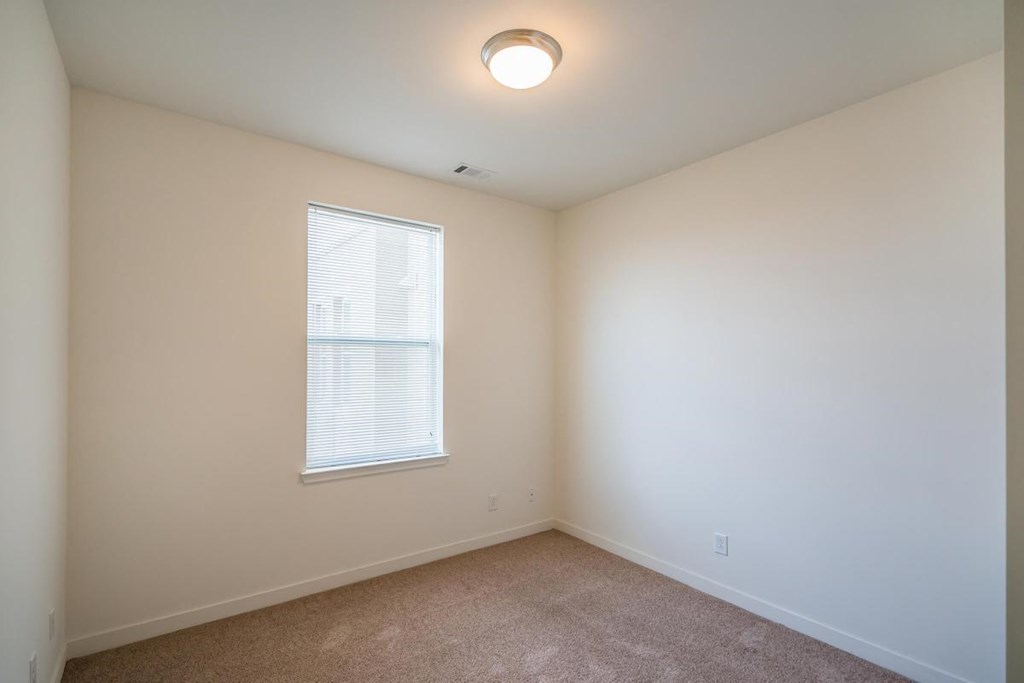 a bedroom with a large window and a carpeted floor