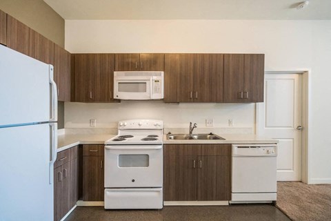 an empty kitchen with white appliances and wooden cabinets