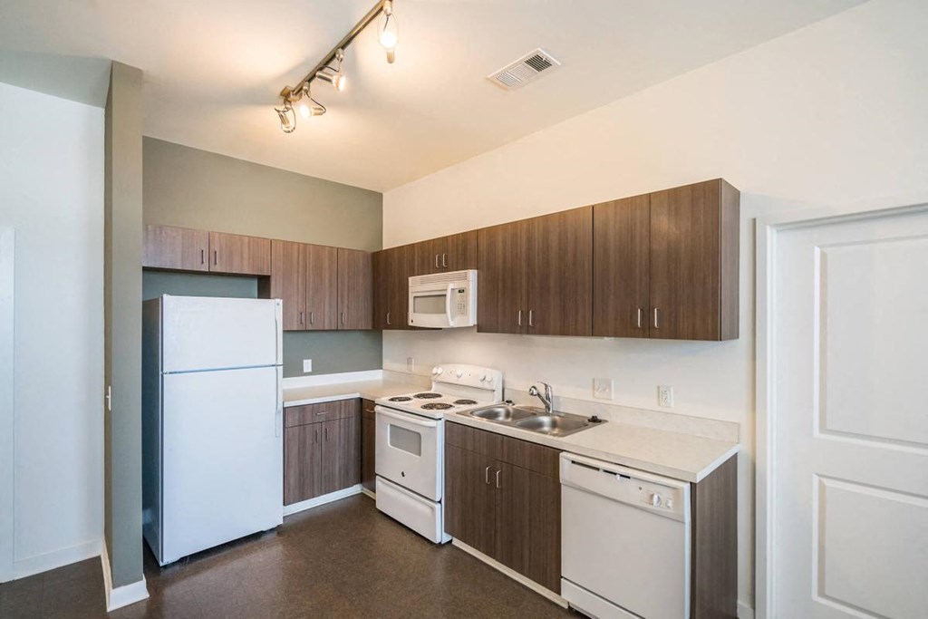 an empty kitchen with white appliances and wooden cabinets