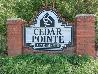 a sign for cedar pointe apartments in front of a brick wall