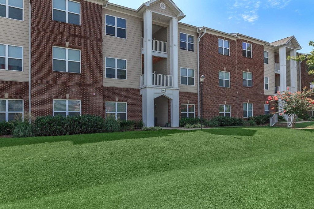 an apartment building with a green lawn in front of it