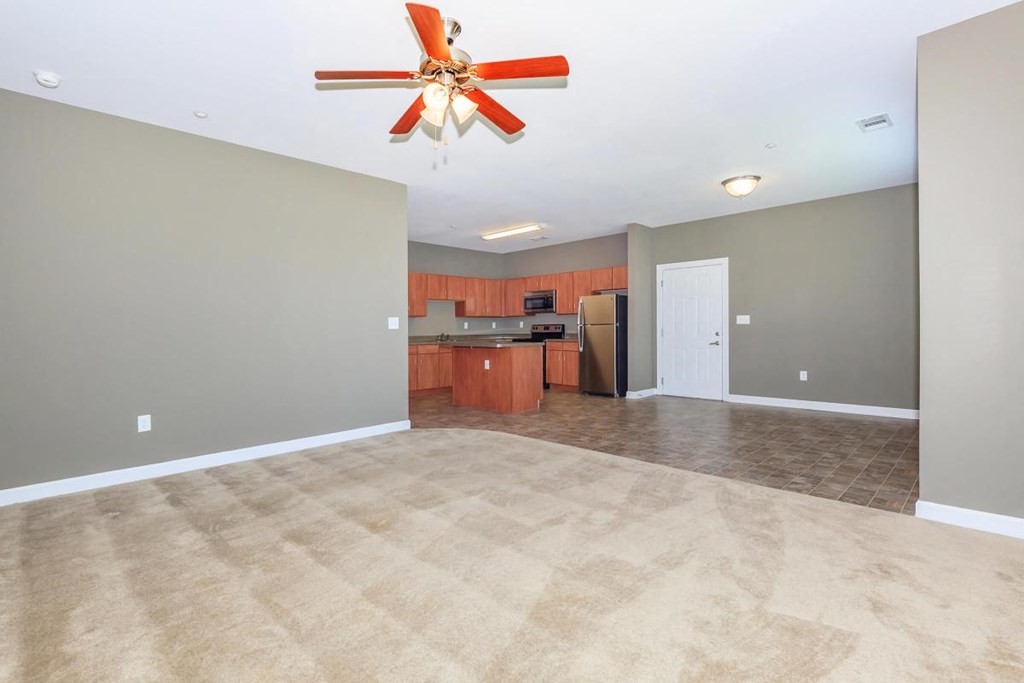 an empty living room and kitchen with a ceiling fan