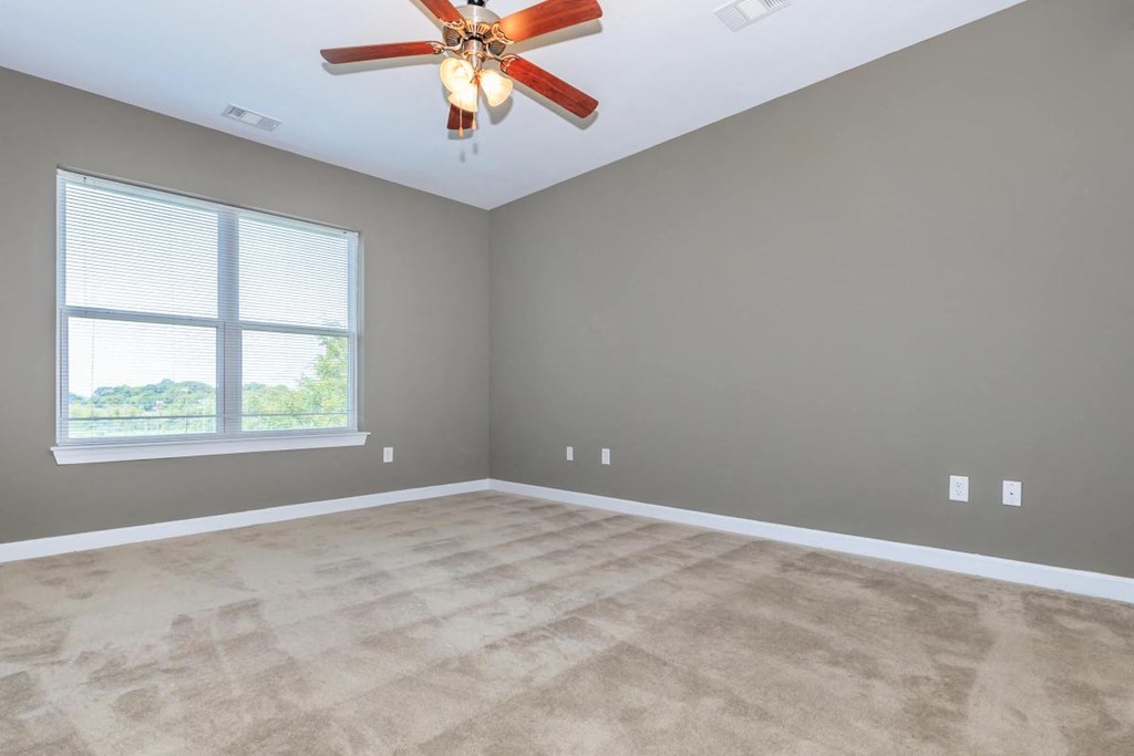 an empty living room with a ceiling fan and a window
