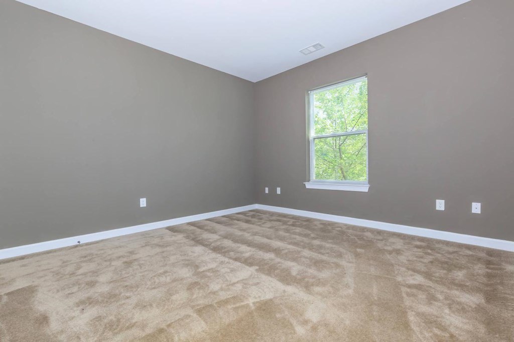 an empty room with brown carpet and a window