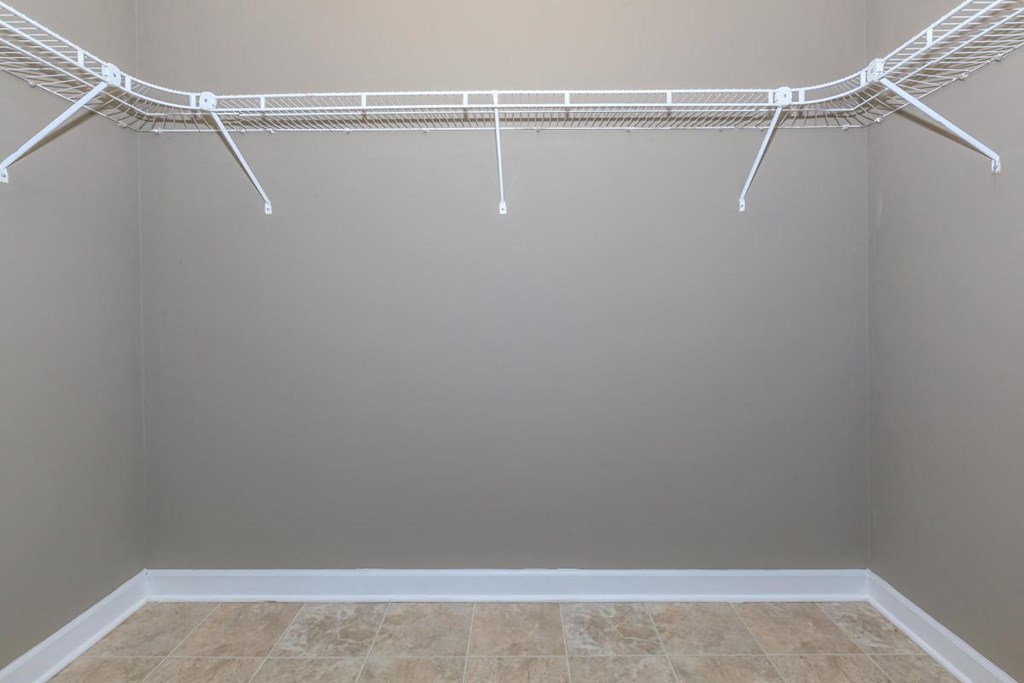 a walk in closet with a wire rack on the wall