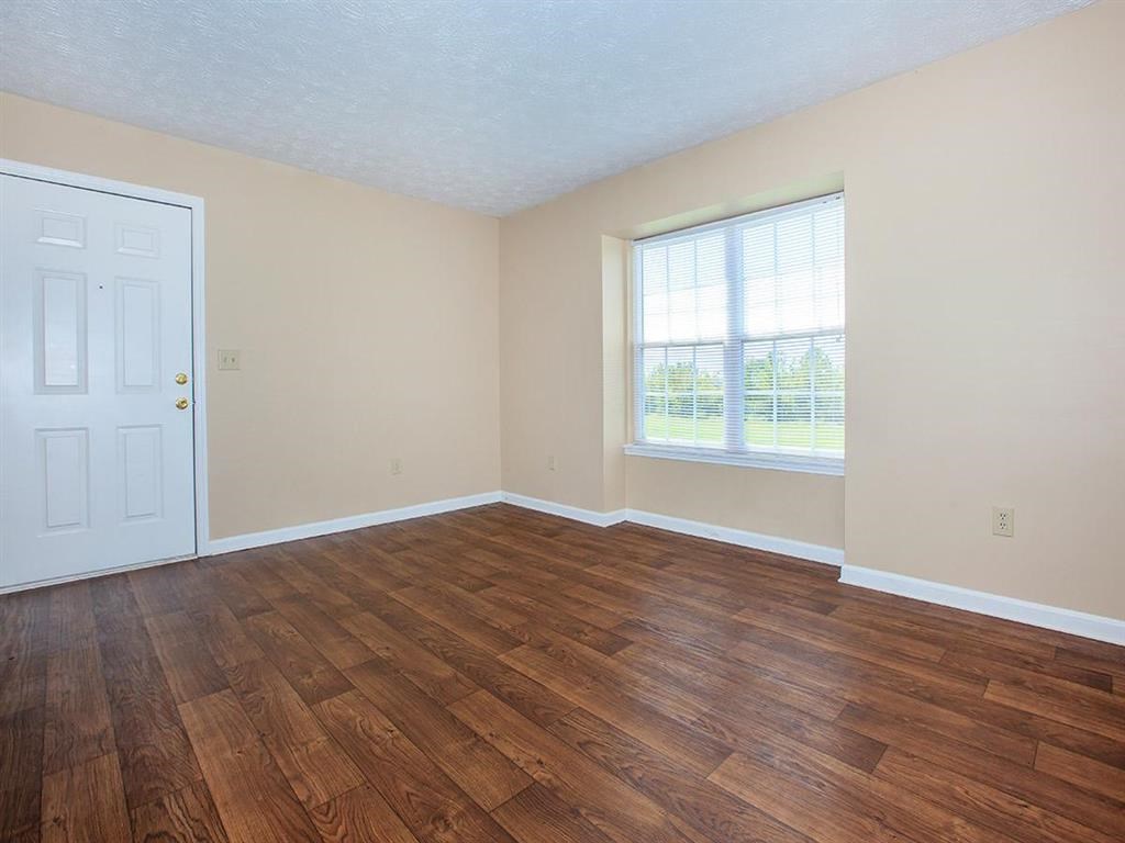 an empty living room with wood flooring and a white door