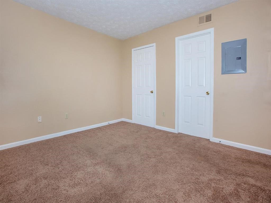 an empty living room with two doors and carpet