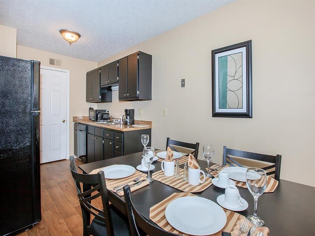a dining room table and a kitchen with a refrigerator