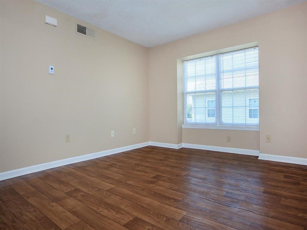 an empty living room with wood floors and a window