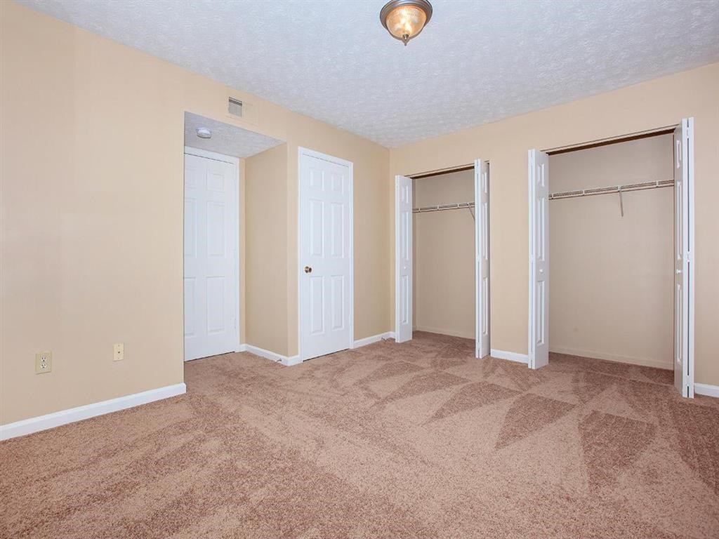 an empty living room with two closets and a carpeted floor