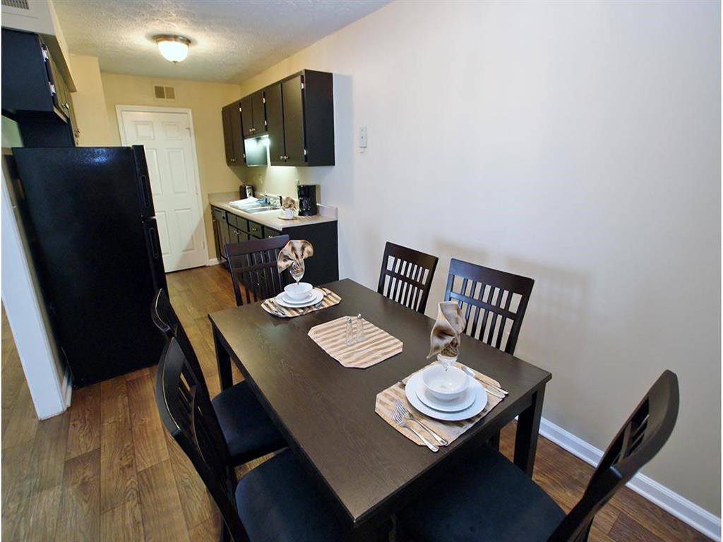 a dining room table and a kitchen with a refrigerator
