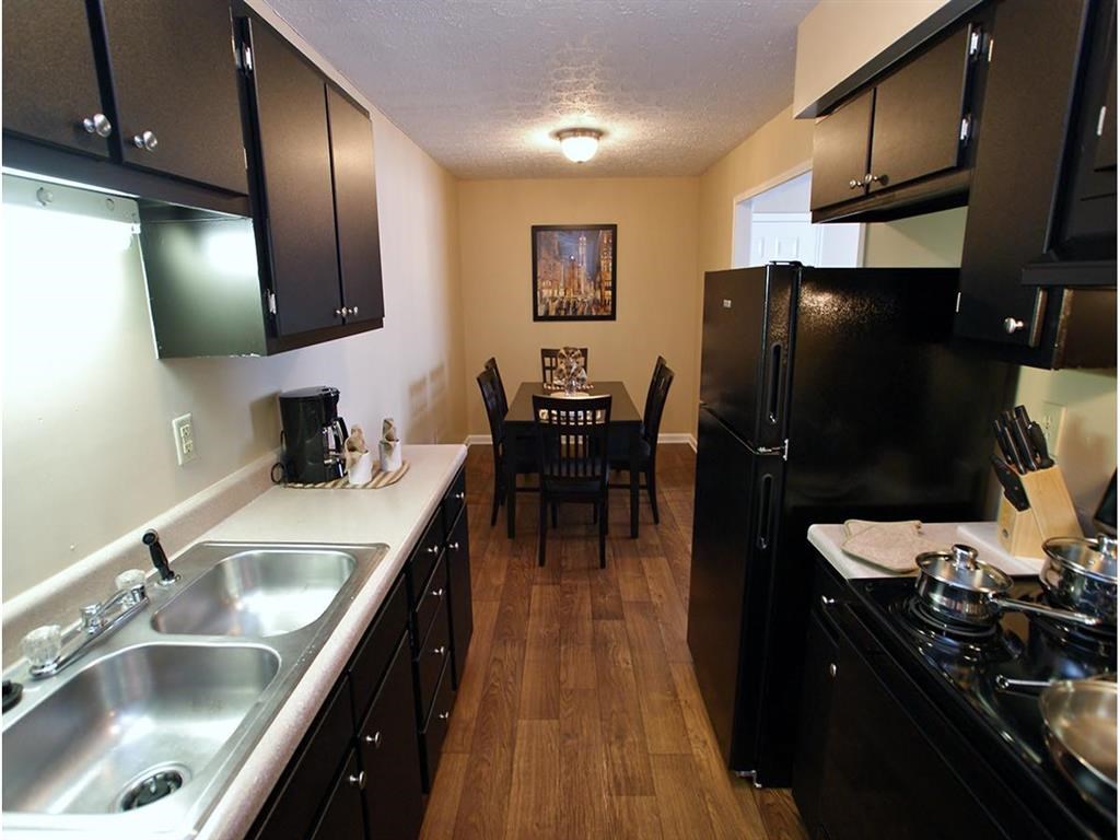 a kitchen and dining room with a black refrigerator and sink