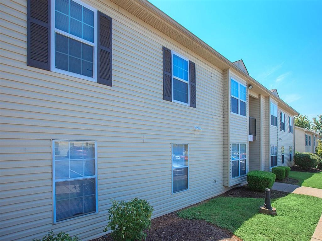 a white building with black shutters and a green yard